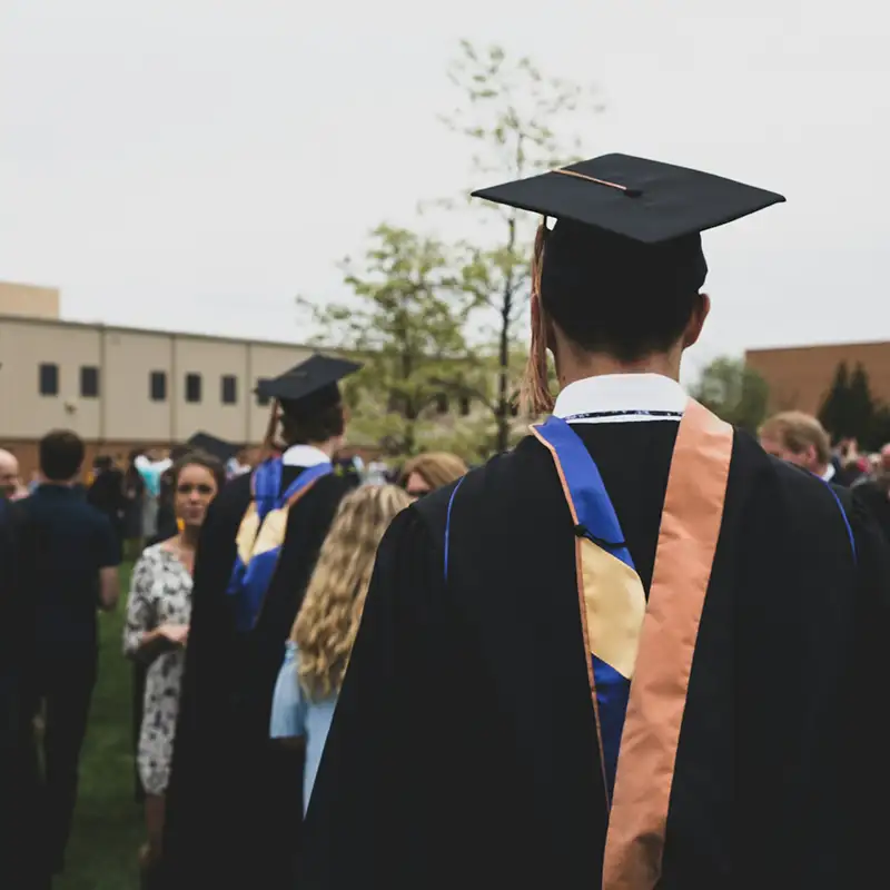 A student at graduation standing with his back to the camera in a crowd of other graduates